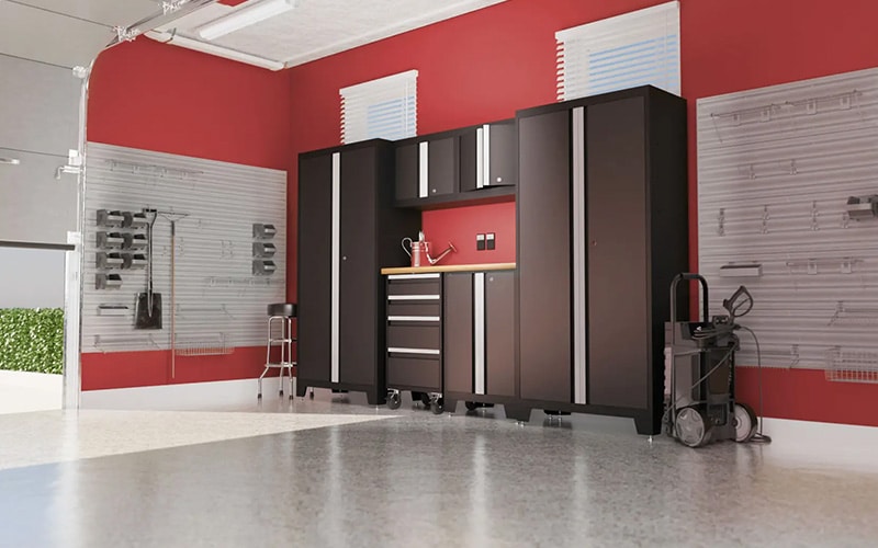 Interior of a remodeled garage with black standup cabinets and slat wall storage.