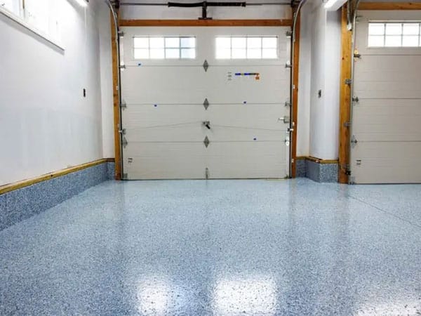 Industrial garage floor with concrete coating with large garage door in background.