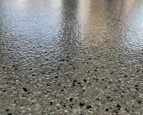 close up of flecked concrete coated garage floor.