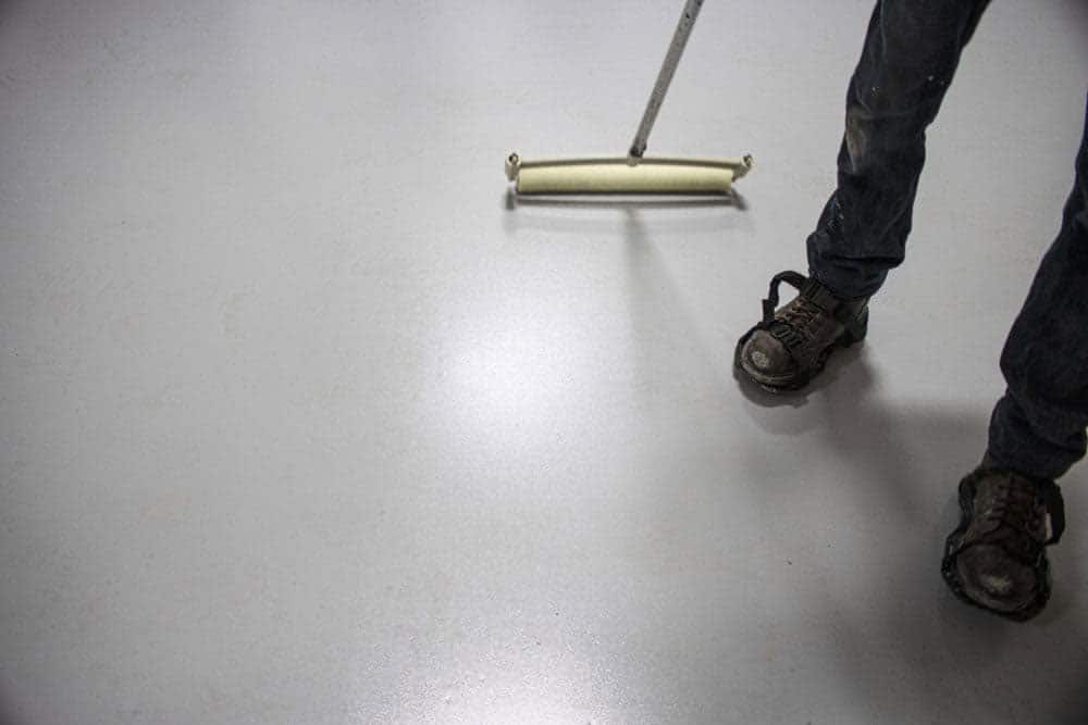 hpigh-performance-epoxy A flat grey concrete coating being rolled on a floor.